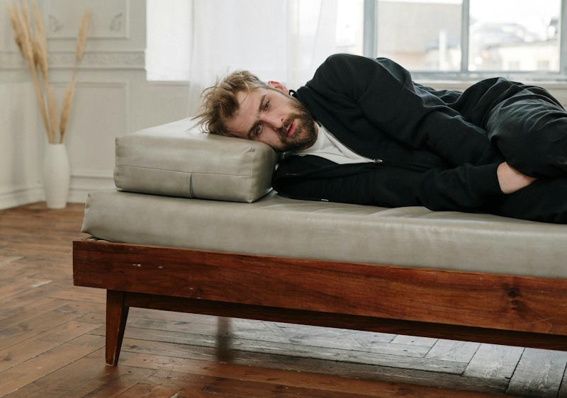 Homme allongé seul sur un canapé, le regard vide, submergé par la solitude après une rupture